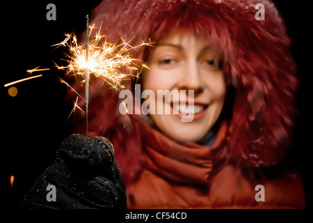 Bella sorridente giovane donna con il Bengala fire in mano isolati su sfondo nero Foto Stock