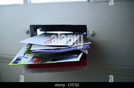 La posta indesiderata in una casa privata letter box essendo inviato attraverso lo sportello anteriore REGNO UNITO Foto Stock