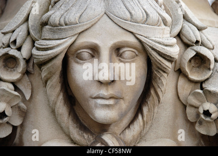 Un intaglio di un volto di donna su un urna di pietra in giardini italiani. Foto Stock