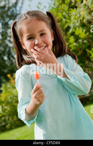 In Germania, in Baviera, Huglfing, ragazza tenendo lollipop in giardino, sorridente, ritratto Foto Stock