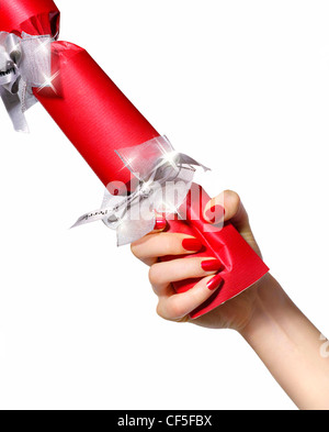 Indossare femmina rosso brillante smalto per unghie tirando un rosso Christmas Cracker con nastro argentato Foto Stock