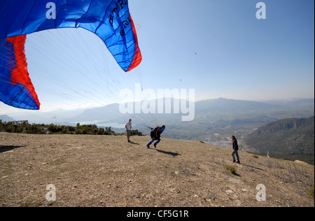 Pilota di parapendio in esecuzione al lancio dalla cima della collina Foto Stock