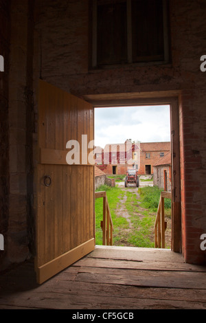 Vista del cortile attraverso una porta aperta di un restaurato Tythe barn. Foto Stock