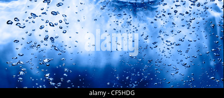 Vista laterale di bollicine d'aria in un liquido di colore blu. Inquadratura orizzontale. Foto Stock