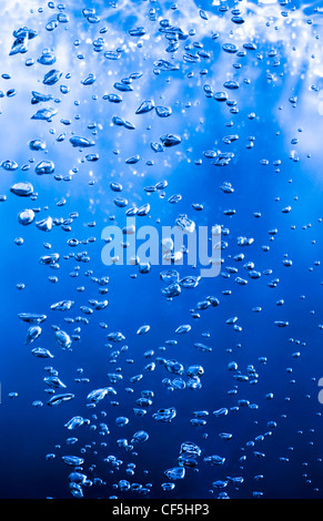 Vista laterale di bollicine d'aria in un liquido di colore blu. Colpo verticale. Foto Stock