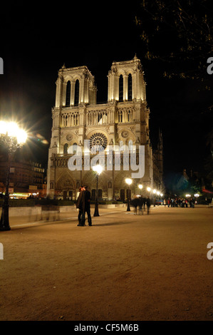 Notre Dame illuminata di notte con un paio di abbracciare in primo piano Foto Stock