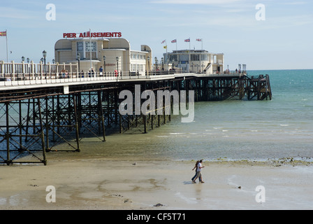 Un giovane a piedi lungo la spiaggia sabbiosa di seguito Worthing Pier. Foto Stock