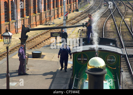 Una locomotiva a vapore assumendo acqua a Sheffield Park stazione sulla ferrovia Bluebell. Foto Stock