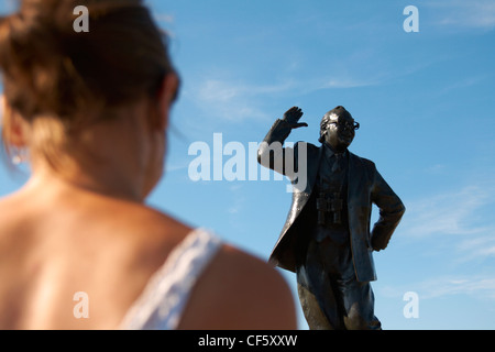 Una donna che guarda la statua di Eric Morecambe su Morecambe fronte mare. Foto Stock