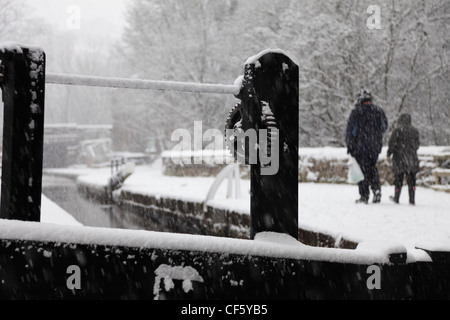 Due persone a piedi lungo una strada alzaia dalla Huddersfield stretto canale nella neve. Foto Stock