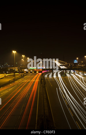 Sentieri di luce dai veicoli che viaggiano da e verso il Dartford Attraversamento di fiume di notte. Foto Stock