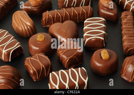 Molti di cioccolato candys appetitosi con la ciliegina su sfondo scuro Foto Stock