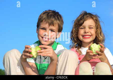 La ragazza e il ragazzo hanno un resto sulla natura, sorridere e mangiare le mele. Foto Stock