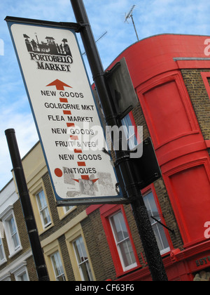 Il Mercato di Portobello segno su un post in Portobello Road di fronte dipinto luminosamente terrazza Vittoriana proprietà. Foto Stock