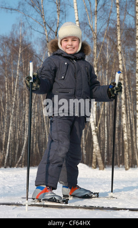 Ragazzo giovane sorge su sci da fondo interno inverno foresta alla giornata di sole Foto Stock