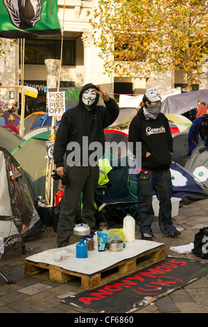 Un occupare Londra protester mostrano segno di pace permanente, mentre con altri manifestanti in mezzo alle tende di fronte St.la Cattedrale di San Paolo Foto Stock