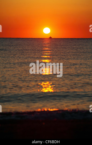 Sun si siede per la linea di orizzonte in mare e si illumina in barca percorso di Sun Foto Stock