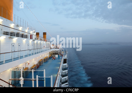 Grande nave da crociera di equitazione in serata. luce su. Alcune delle persone sul ponte. Foto Stock