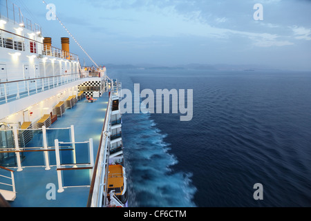 Grande nave da crociera di equitazione in serata. luce su. Alcune delle persone sul ponte Foto Stock