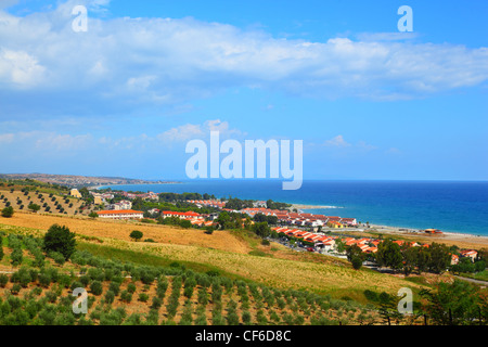 Case bianche sulla costa vicino colle verde con alberi e cespugli Foto Stock