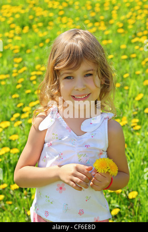 Bambina sorge sul campo e detiene il tarassaco Foto Stock