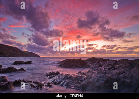 Inverno sunrise crea Nuvole rosa a Lantivet Bay nel sud-est della Cornovaglia nel giorno di Capodanno. Foto Stock