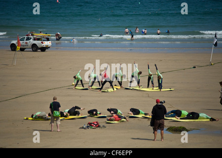 Surfers in fase di riscaldamento sulla spiaggia presso una scuola di surf a Towan Beach, Newquay. Foto Stock