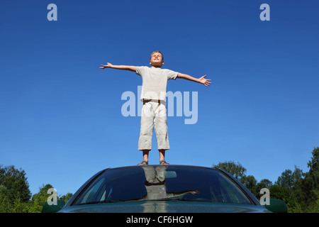 Bambino si alza sulla testa di auto sollevamento testa a sky e conduce le mani ai lati Foto Stock