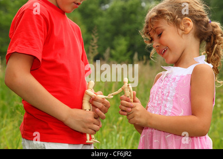 Piccolo fratello e sorella gioca con poco legno manichini in natura. manichini salutarci. concentrarsi sui manichini. Foto Stock