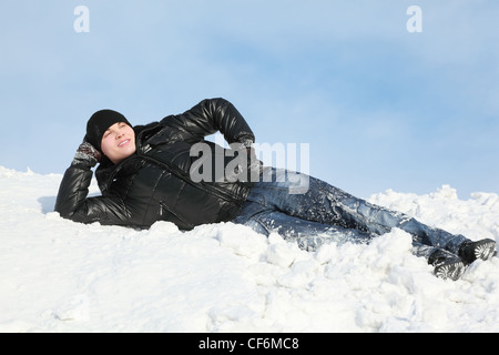 Giovane uomo giace sulla neve il supporto Palm e guarda lontano nel cielo Foto Stock