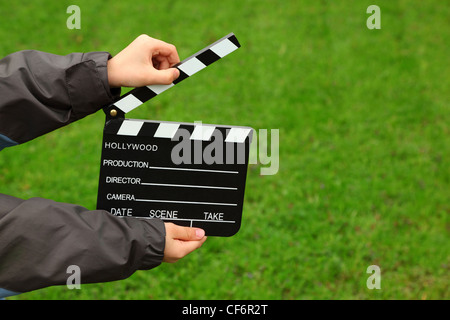 Cinema battaglio pensione in mani del ragazzo in camicia sul campo con erba verde Foto Stock