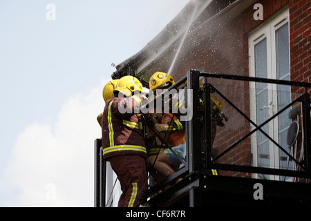 I vigili del fuoco fanno un drammatico salvataggio da un balcone come fuoco rip attraverso il tetto sopra di loro Foto Stock