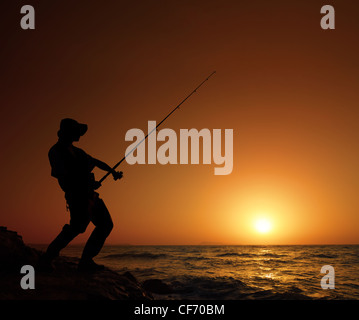 Un giovane pescatore di pesca con tramonto in background Foto Stock