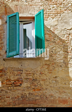 Verde persiane di legno su un esposto un muro di mattoni in Toscana Foto Stock