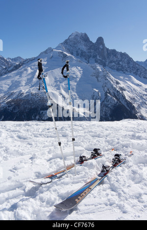 Sci e bastoncini da sci sulla neve con le Aiguilles Verte e Les Drus in background Foto Stock