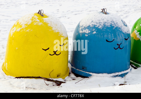 Copertura di neve bidoni in plastica per lo smistamento dei rifiuti. Giallo blu e verde con disegno in inverno. Foto Stock