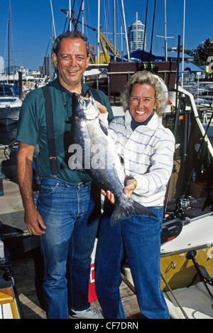 Un fisherwoman mostra con orgoglio un salmone chinook ha catturato su una carta sportfishing barca che funziona da Vancouver, British Columbia, Canada. Foto Stock