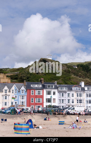 Le persone che si godono la spiaggia sabbiosa prima di case colorate di Aberdovey Promenade & Scogliera Lookout, Aberdyfi, Galles del Nord, Regno Unito Foto Stock