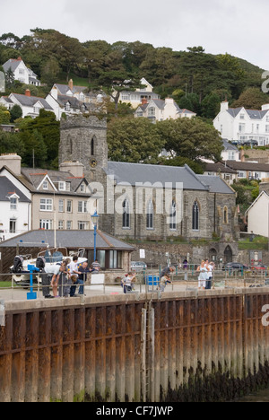 Famiglie Attività di pesca del granchio off il molo a Aberdovey, prima della pittoresca spiaggia di fronte case e la chiesa di San Pietro, Aberdyfi, Wales, Regno Unito Foto Stock
