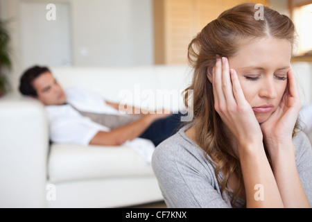 Donna sperimentare mal di testa con l'uomo sul divano dietro di lei Foto Stock