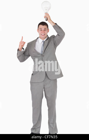 Ritratto di un imprenditore tenendo una lampadina sopra la sua testa mentre sta puntando a qualcosa di Foto Stock