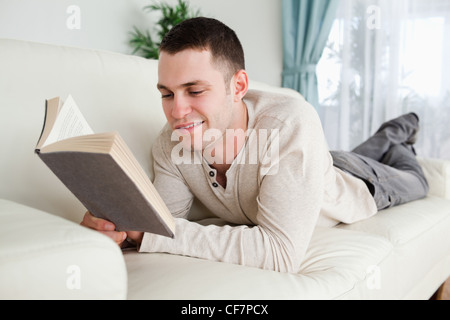 Giovane uomo sdraiato su un lettino per leggere un libro