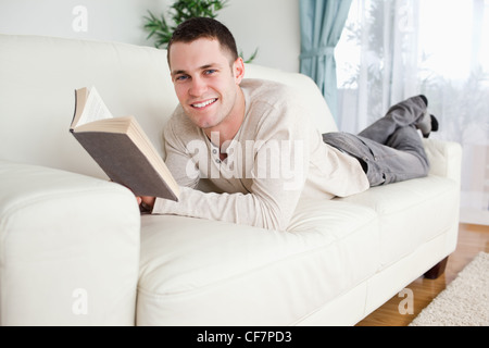 Giovane uomo sdraiato su un lettino la lettura di un libro