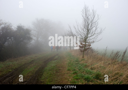 Gruppo di escursionisti nella nebbia in un paese via Foto Stock