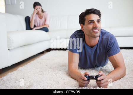 Uomo di giocare con i videogiochi mentre la sua ragazza è sempre pazza di lui Foto Stock