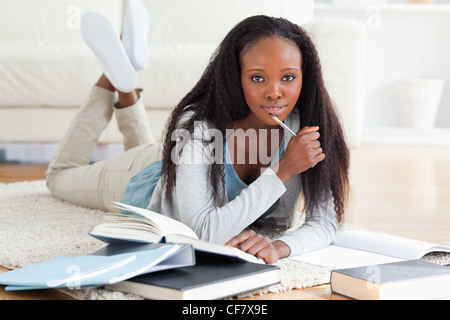 Studentessa giacente su un tappeto a studiare Foto Stock