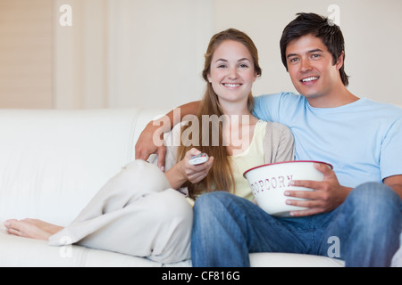 Coppia giovane di guardare la televisione mentre mangiare popcorn Foto Stock