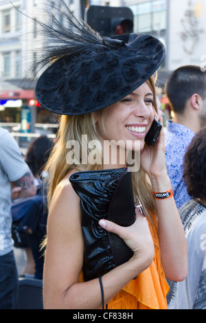 Moda Donna parlando al telefono cellulare proveniente da Melbourne corse di cavalli presso la stazione di Flinders Street, Melbourne, Australia Foto Stock