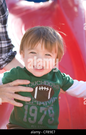 Un anno vecchio ragazzo cercando felice scorrere una slitta di colore rosso. Foto Stock