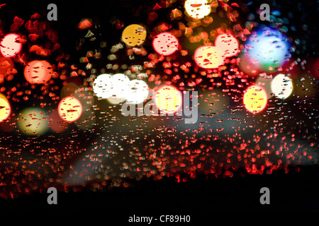 Vista attraverso il bagnato parabrezza auto, traffico, notte, città. Foto Stock